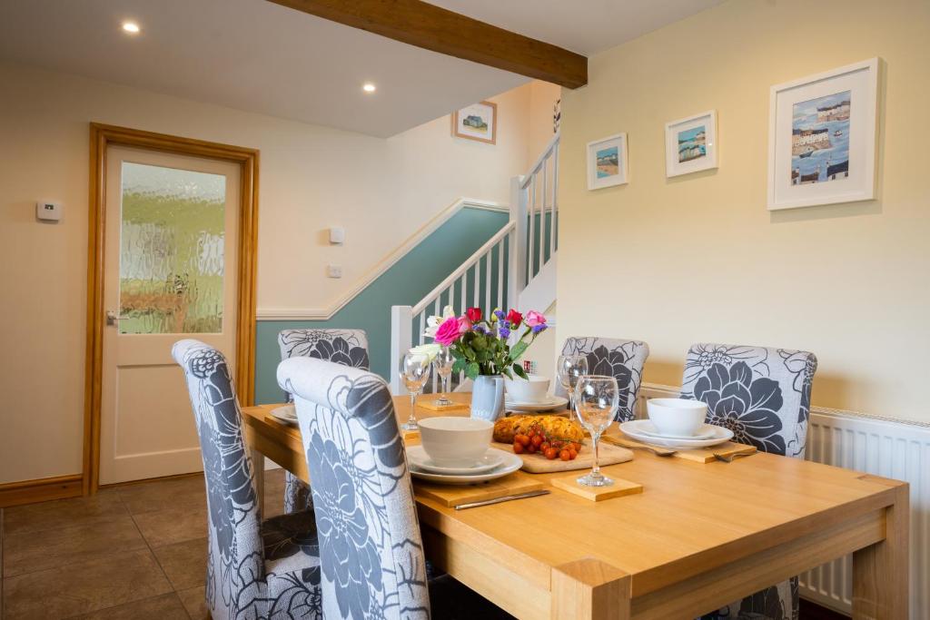 een eetkamer met een houten tafel en stoelen bij Bennar Isa Cottages Dyffryn Ardudwy in Barmouth