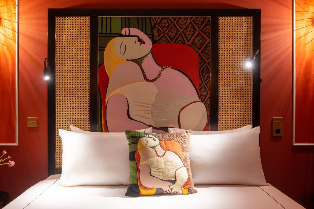 uma cama com uma cabeceira com um quadro atrás em Mom'Art Hotel em Paris