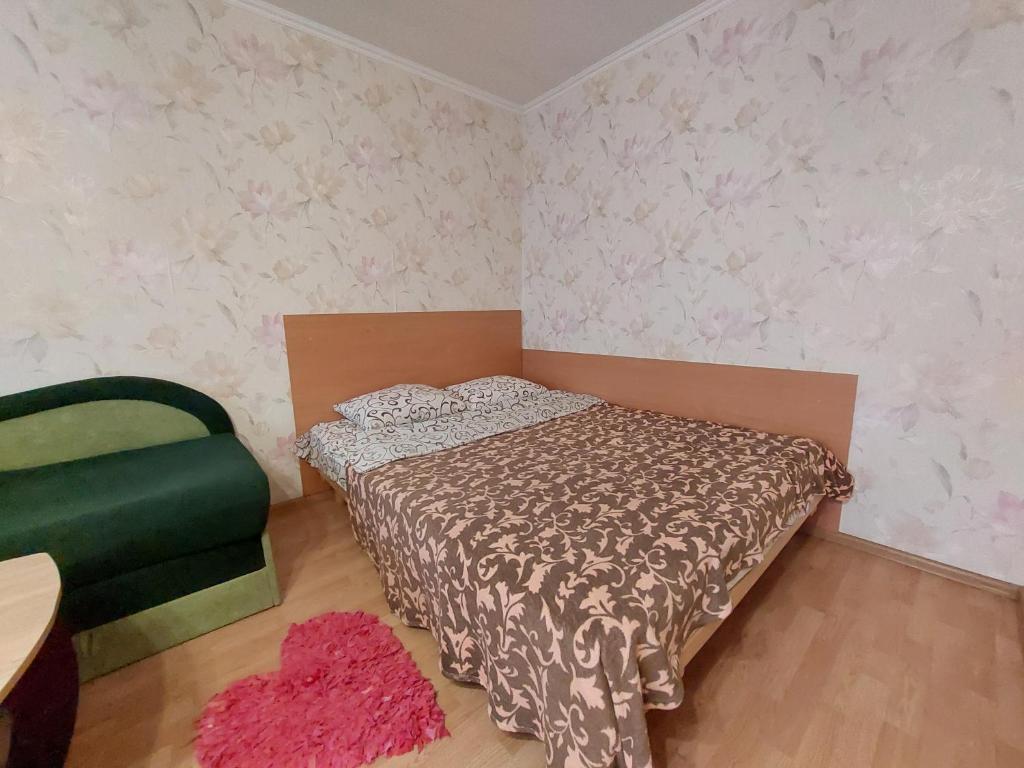 - une petite chambre avec un lit et une chaise verte dans l'établissement Апартаменти економ, à Loutsk