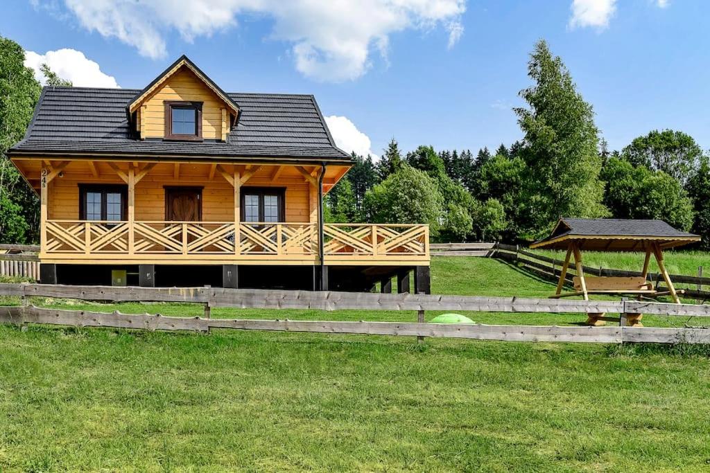 a wooden house in a field with a gazebo at Domek w Klisiówkach in Ujsoły