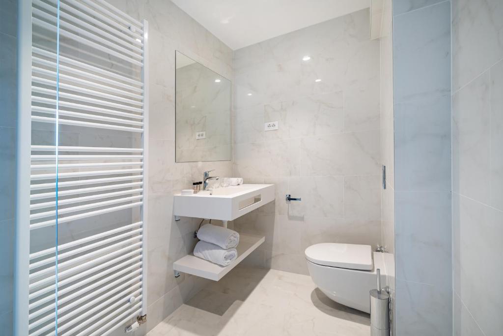 a white bathroom with a toilet and a sink at Miramare Hotel in Zadar