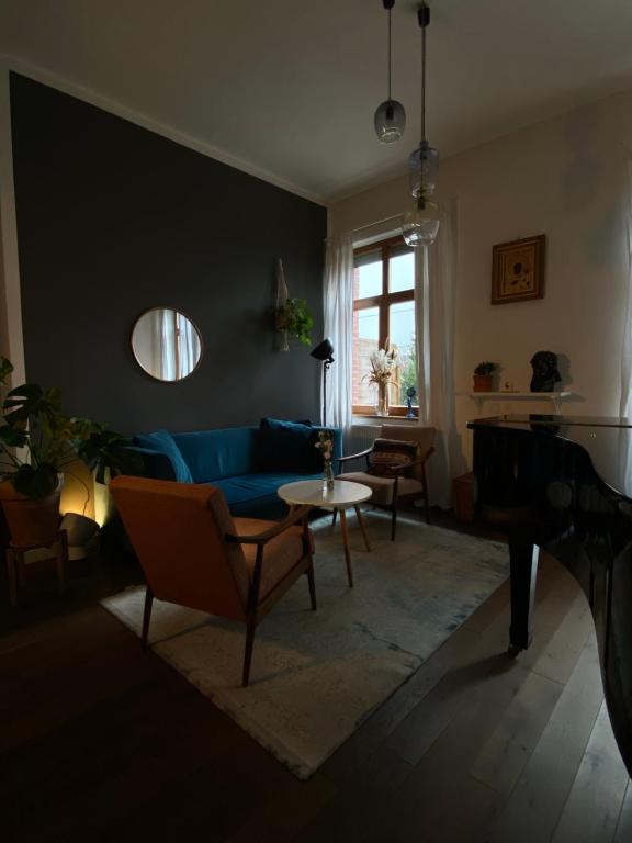 een woonkamer met een blauwe bank en een tafel bij Kraków Piano Apartment in Krakau