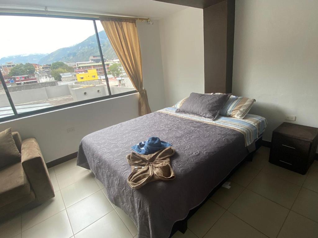 a bedroom with a bed with a hat and a window at GIGAHOUSE in Baños