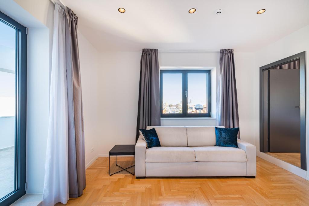 a living room with a white couch and a window at Miramare Hotel in Zadar