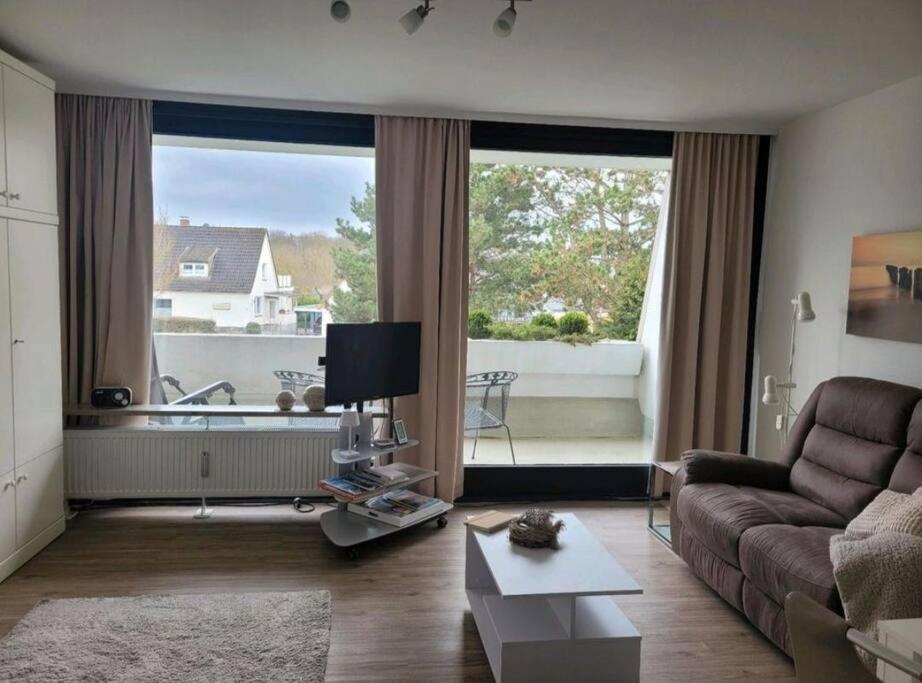 a living room with a couch and a large window at Scharbeutz, 1 Raum Fewo mit sonnigem Balkon, ruhig und zentral in Scharbeutz