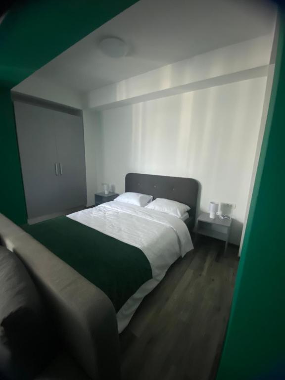 um quarto com uma cama grande com lençóis brancos e verdes em Green Studio em Mamaia Nord – Năvodari