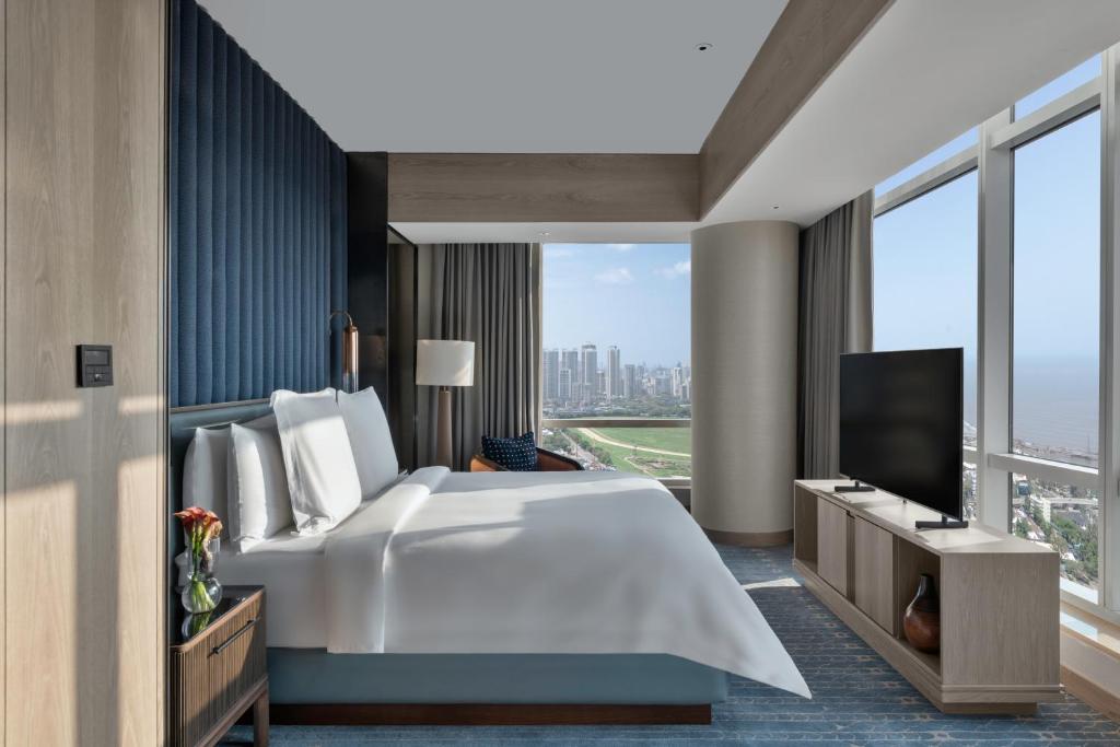 a bedroom with a large white bed and a large window at Four Seasons Hotel Mumbai in Mumbai