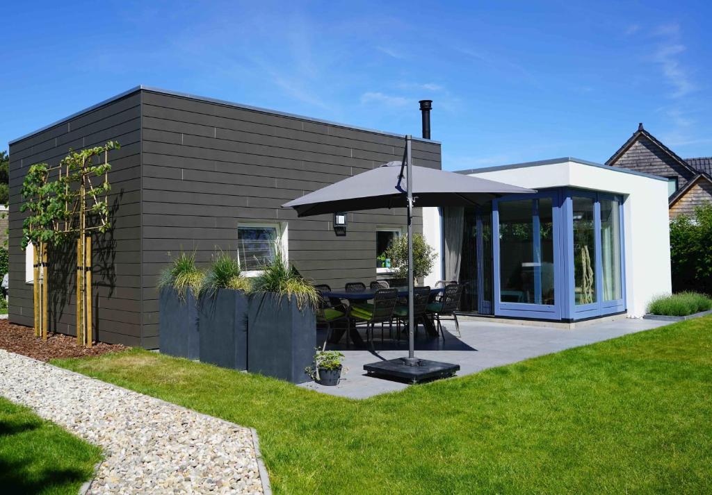 ein Haus mit einem Sonnenschirm und einer Terrasse in der Unterkunft Texel Boogaloo in De Koog