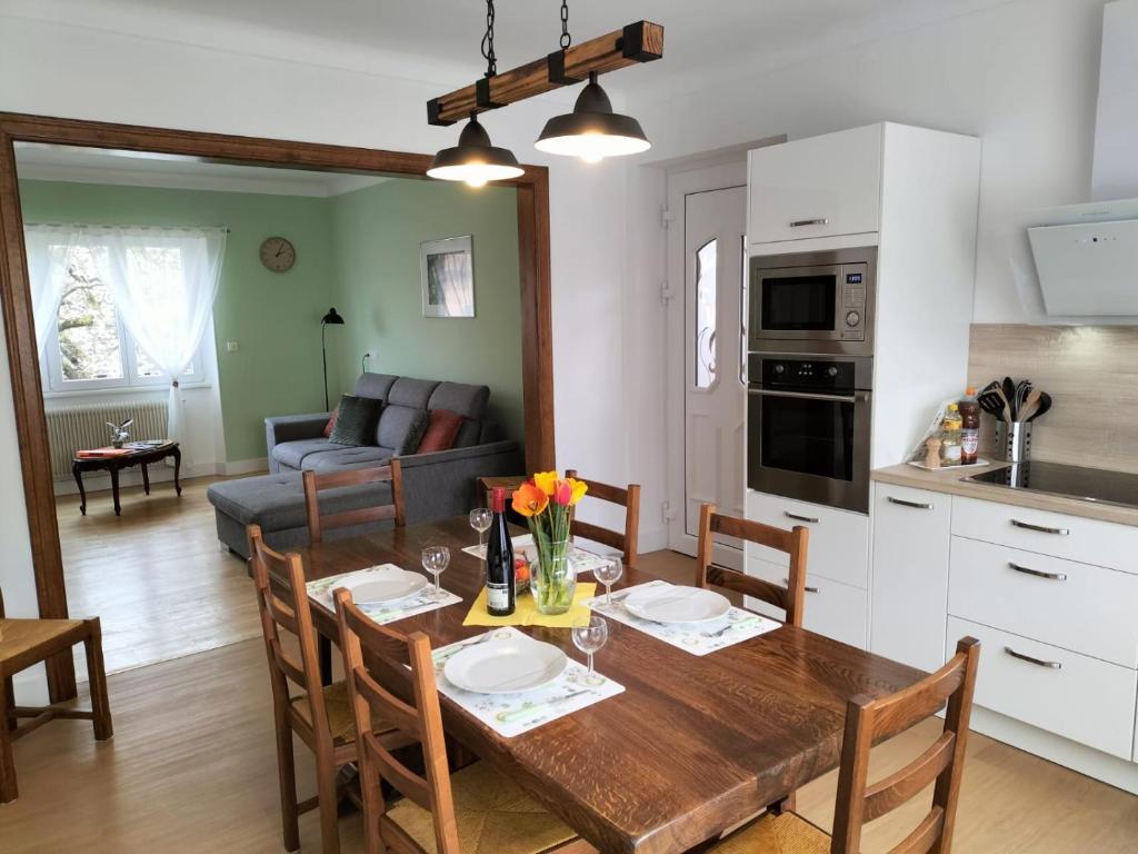 cocina y sala de estar con mesa de madera y sillas en gîte le carthame, en Elsenheim
