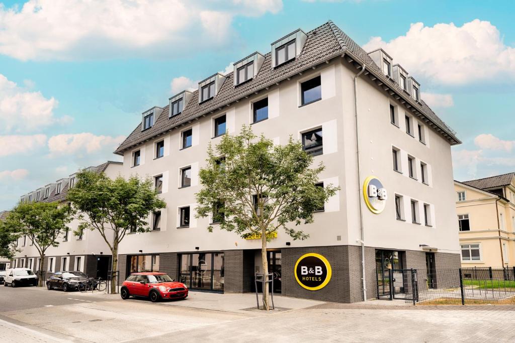 基森的住宿－B&B Hotel Gießen，一座白色的建筑,前面有一辆红色的汽车