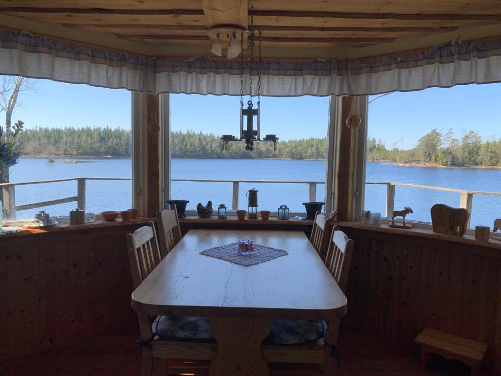 a dining room with a table and a view of the water at Sävsjön in Mjöbäck