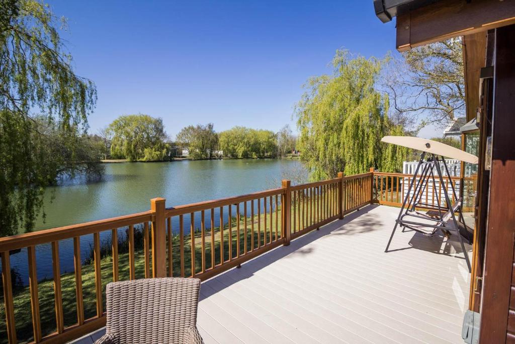 una terraza con sillas y vistas al río en Stunning Lodge With Free Wifi For Hire At Carlton Meres In Suffolk Ref 60013m en Saxmundham