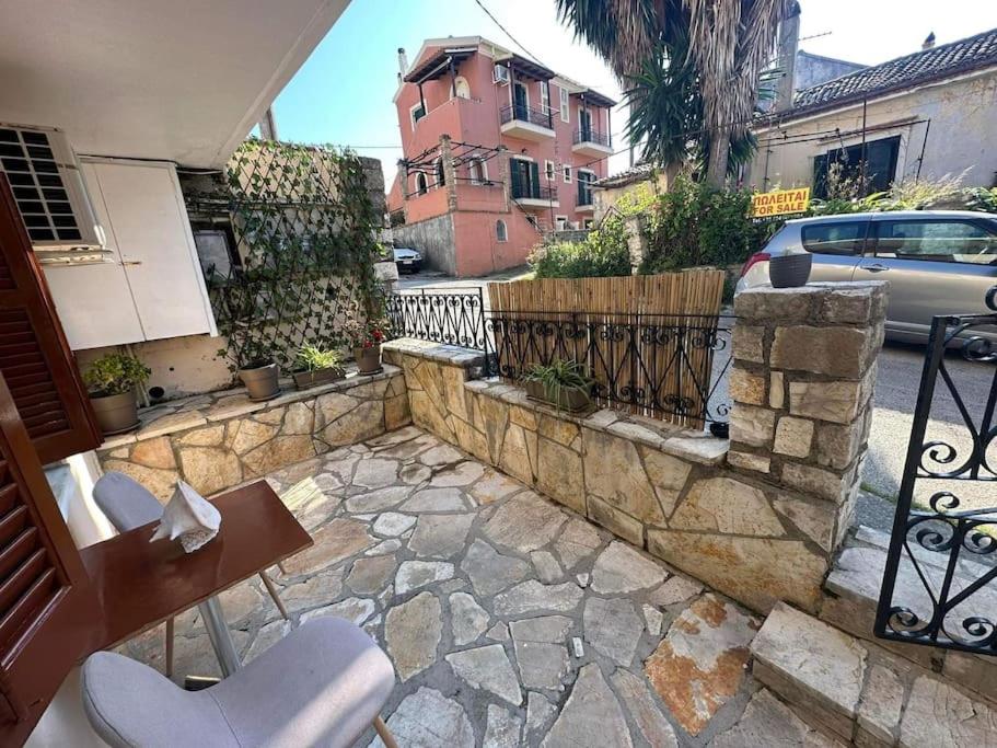 a patio with a stone fence and a table and chairs at Mon Repo Apartment Corfu in Corfu Town
