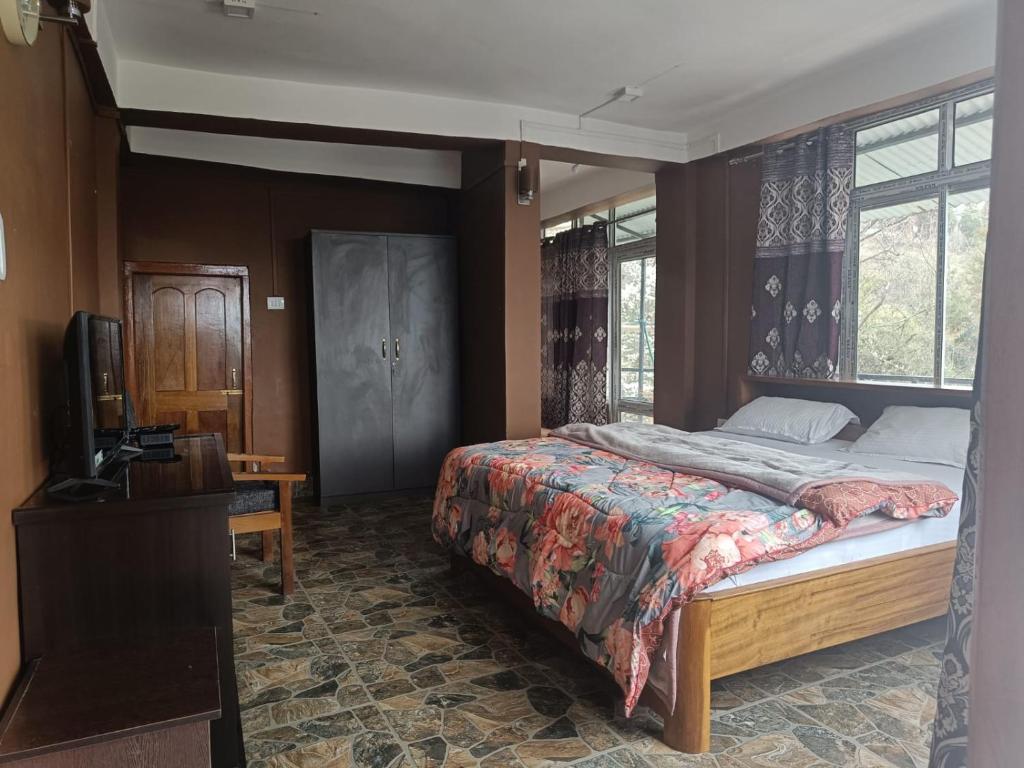 een slaapkamer met een bed en een televisie. bij Vamoose Mountain Mist in Tawang