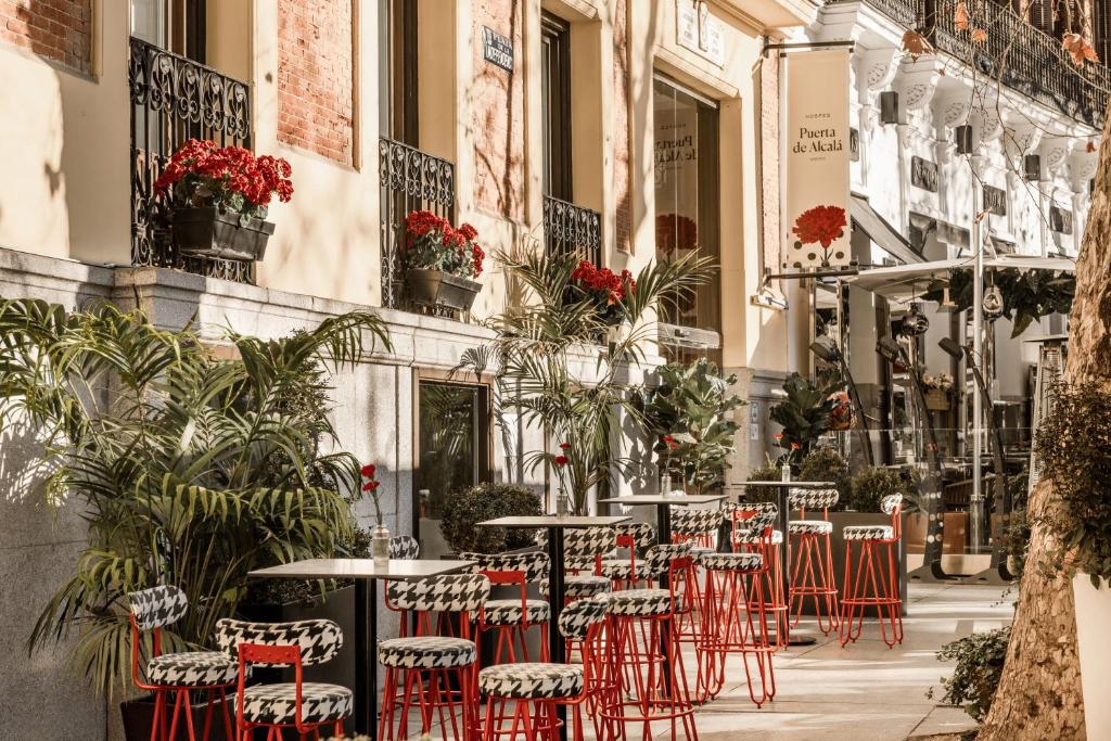 a row of tables and chairs on a street with plants at Hospes Puerta de Alcalá, a Member of Design Hotels in Madrid