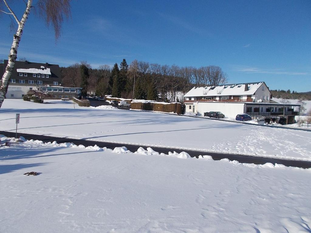 un aparcamiento cubierto de nieve con casas en Haus Bergeshöh Hochsauerland, en Eslohe