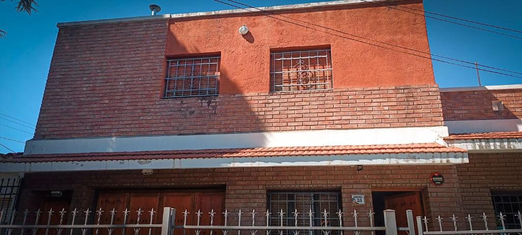 un edificio de ladrillo rojo con una valla delante en Departamento HOSPITAL PRIVADO - MATERNIDAD - QUALITY - CORDOBA en Córdoba