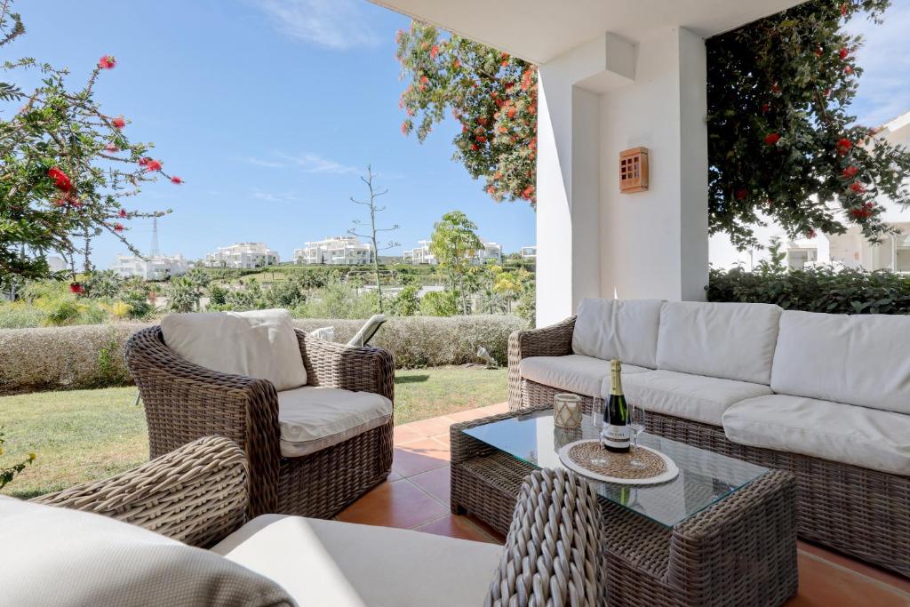 un patio con sofá, sillas y mesa en Lagoon suites en Casares