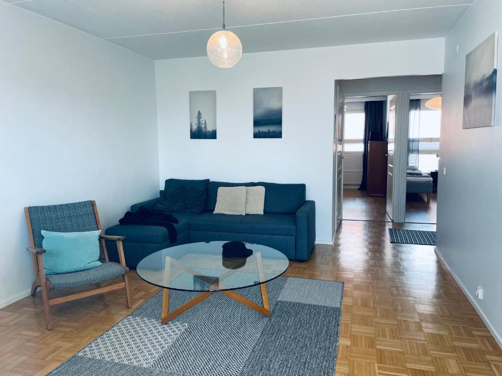 a living room with a blue couch and a glass table at Kalastajankuja Apartment in Espoo