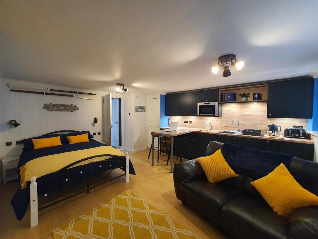 a bedroom with a bed and a couch and a kitchen at Hayling Hideaway, private cosy annex near to beach in South Hayling