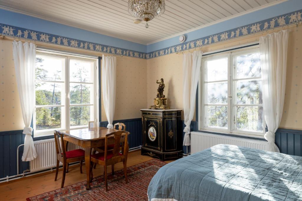 Schlafzimmer mit einem Bett, einem Schreibtisch und Fenstern in der Unterkunft Villa Sofia Barösund in Inkoo