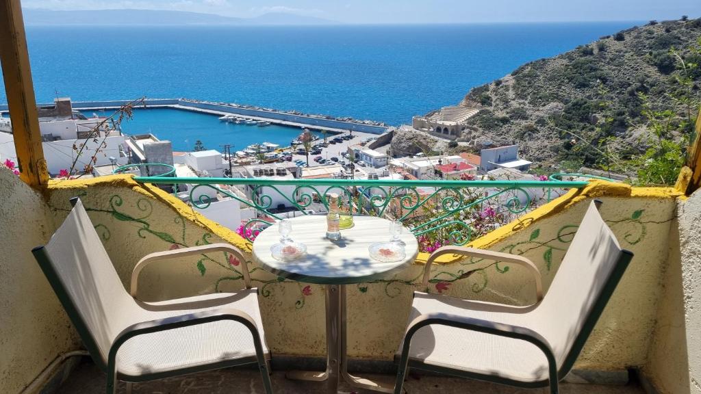 a table and chairs on a balcony with a view of the ocean at Erofili Rooms in Agia Galini