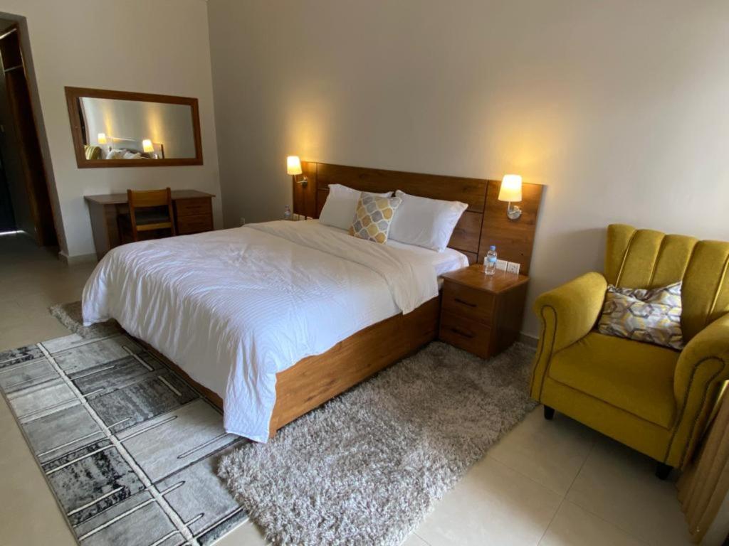a bedroom with a bed and a yellow chair at Maravilla Kivu Eco Resort 