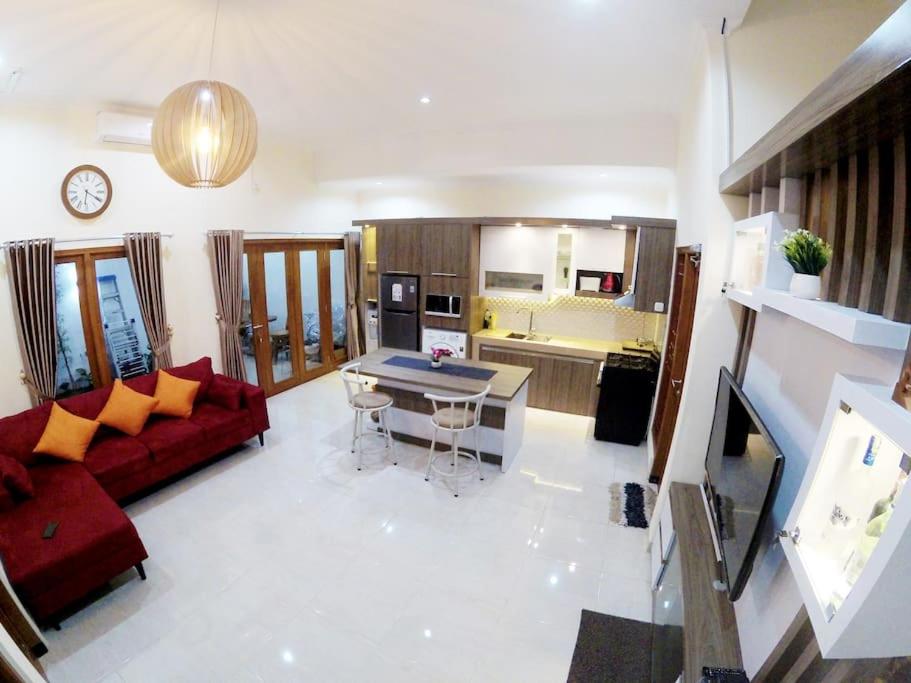 a living room with a red couch and a kitchen at Rumah Bungur, Purwomartani in Kalasan