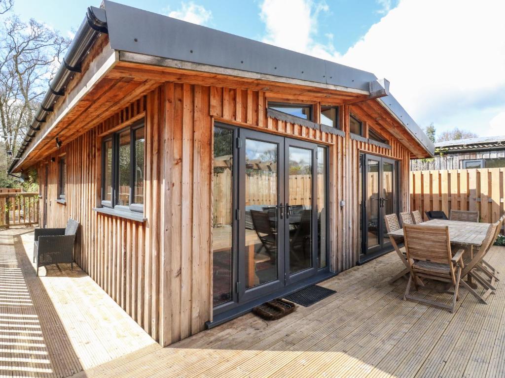 a wooden cabin with a table and chairs on a deck at Gloccamaura in Newton Abbot