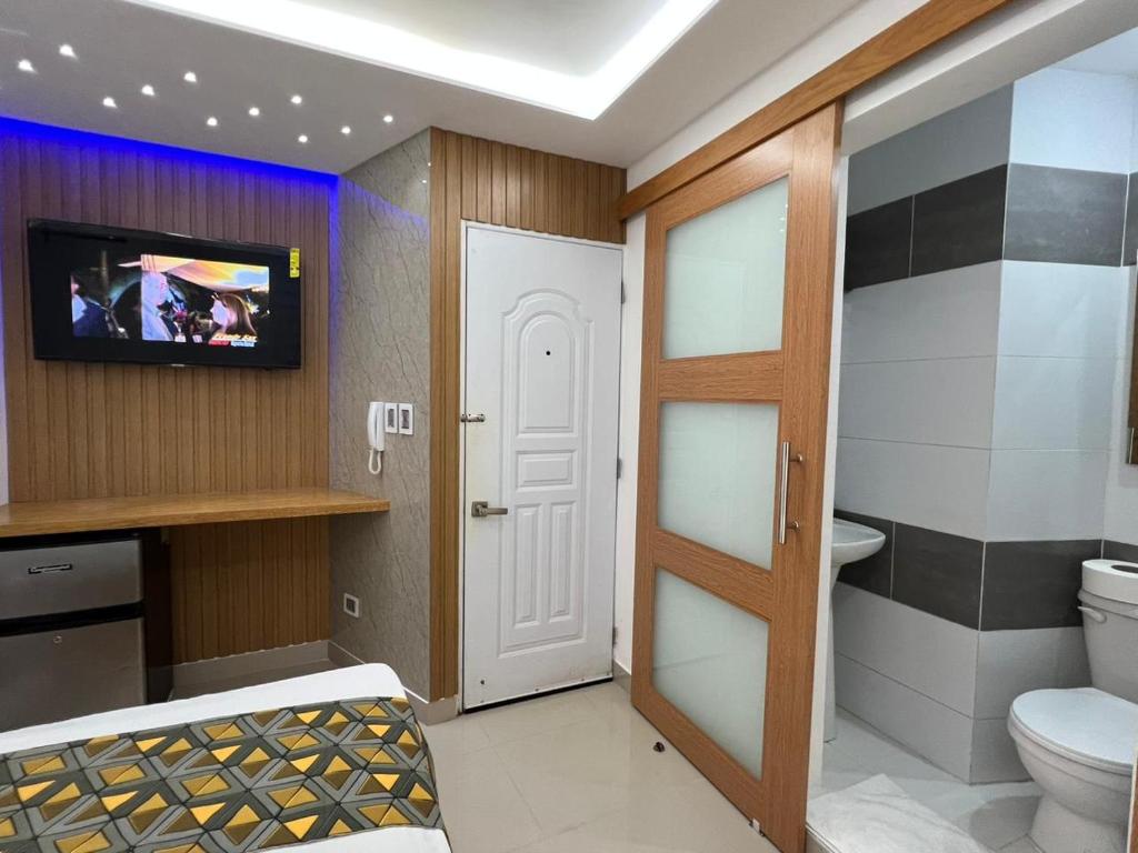 サンティアゴ・デ・ロス・カバリェロスにあるAlegria Hostalのバスルーム(トイレ付)、壁にテレビが備わります。