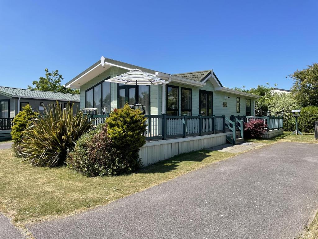 a house with a front porch with an umbrella at Beautiful 6 Berth Lodge At Cherry Tree Holiday Park Ref 70002tg in Great Yarmouth