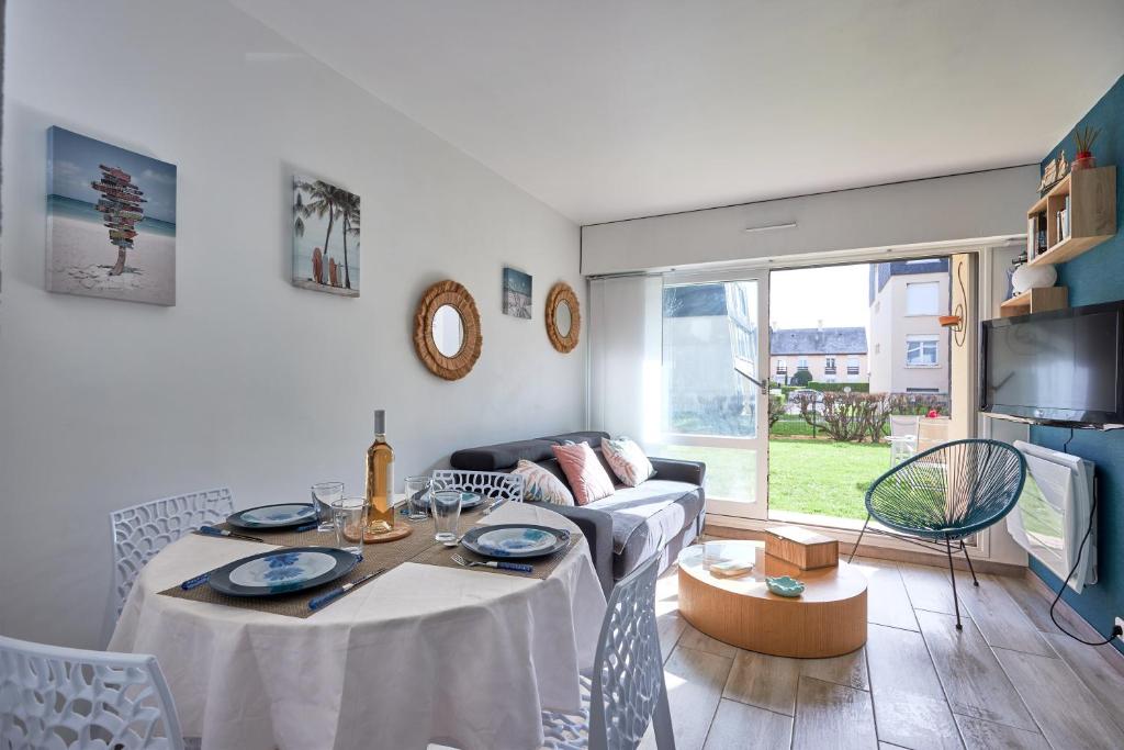 uma sala de estar com uma mesa e um sofá em Overlord - Appt 300m plage em Courseulles-sur-Mer