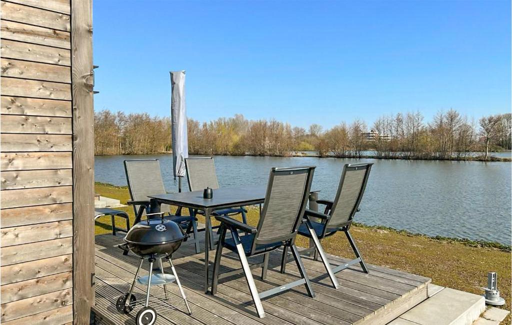 a table and chairs sitting on a deck next to a lake at Beautiful Home In Tossens With Lake View in Tossenserdeich