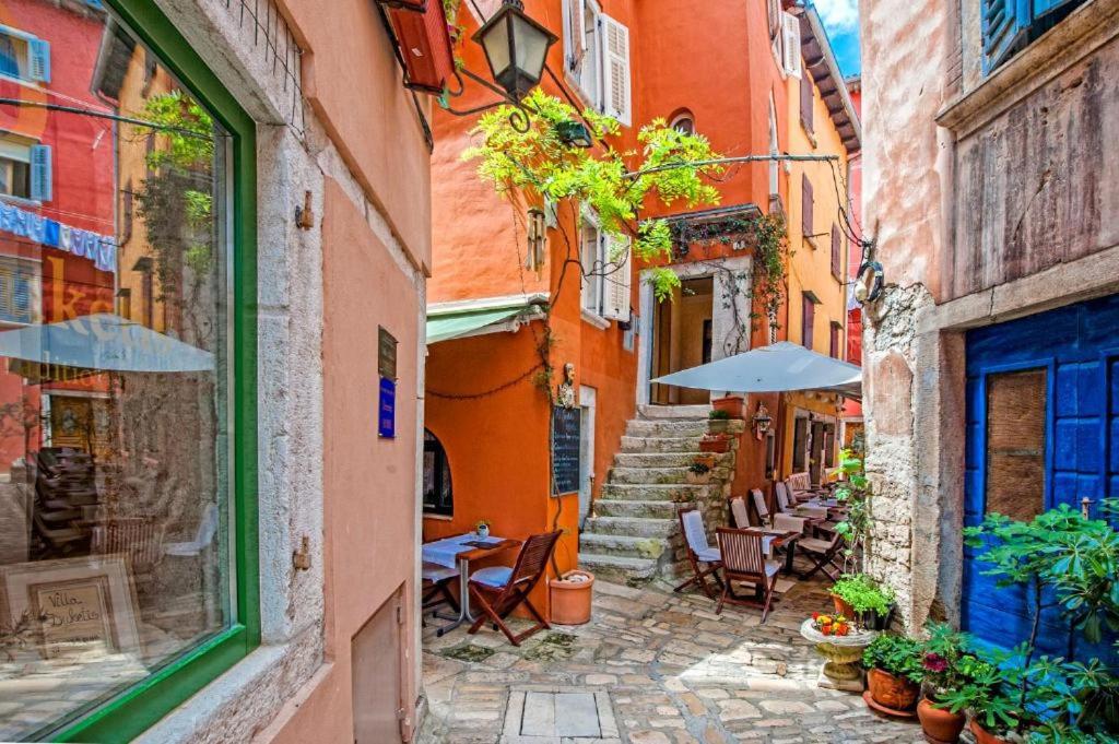 an alley in an old town with tables and umbrellas at Apartments Casa Rubeus Rovinj in Rovinj