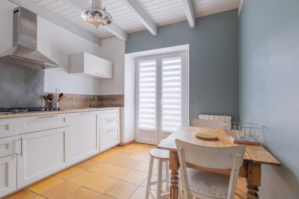 eine Küche mit weißen Schränken und einem Holztisch in der Unterkunft Seabird - Belle maison pour 8 in Camoël