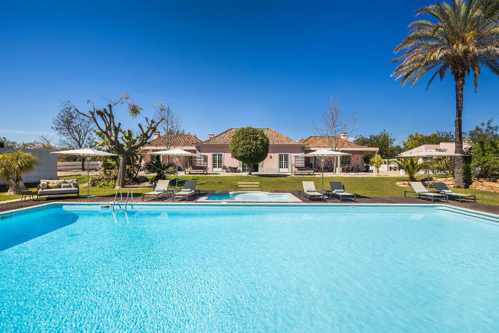 a large swimming pool in front of a house at Quinta de Santa Margarida - Charm Country House in Tavira