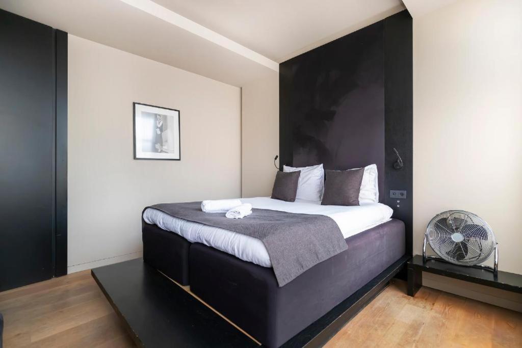 a bedroom with a black and white bed and a fan at AmsterHome Hotel in Amsterdam