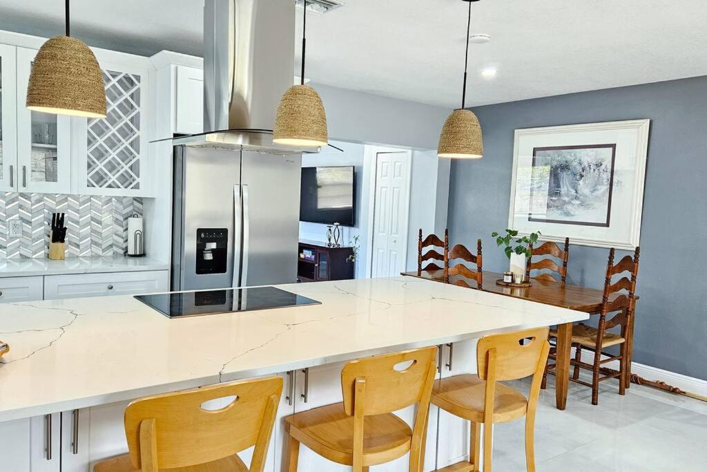 a kitchen with a white counter and wooden chairs at Paradise Vacation Home in Boynton Beach