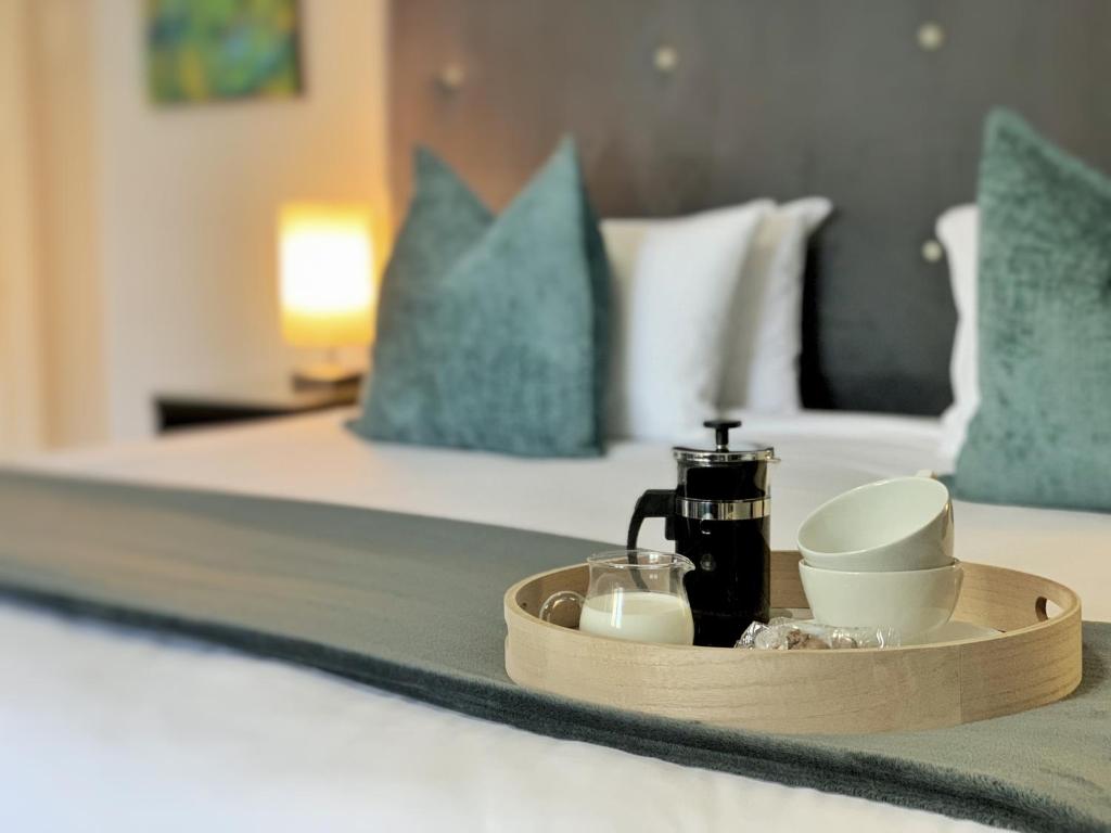 ein Tablett mit einer Kaffeemaschine und Tassen auf einem Bett in der Unterkunft 4 on Varneys Guest House - We have uninterrupted power in Kapstadt