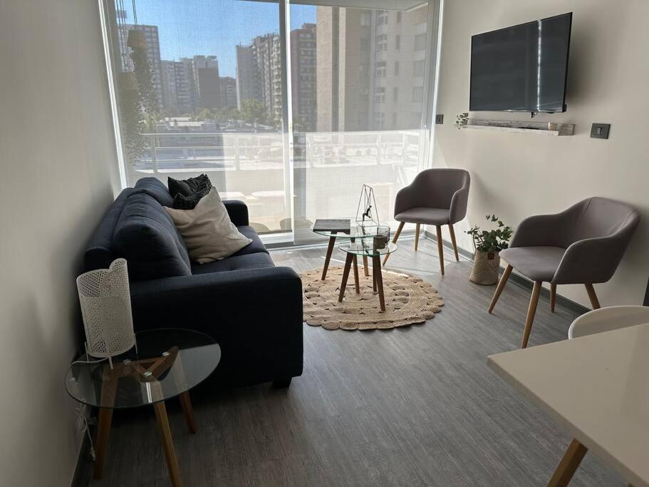 ein Wohnzimmer mit einem Sofa und einem großen Fenster in der Unterkunft Depto 1H 1B con Balcón, excelente conectividad in Santiago