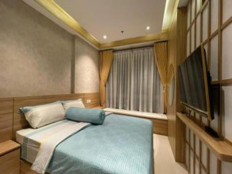 sypialnia z łóżkiem, telewizorem i oknem w obiekcie Borneo Bay City Apartment Balikpapan w mieście Klandasan Kecil