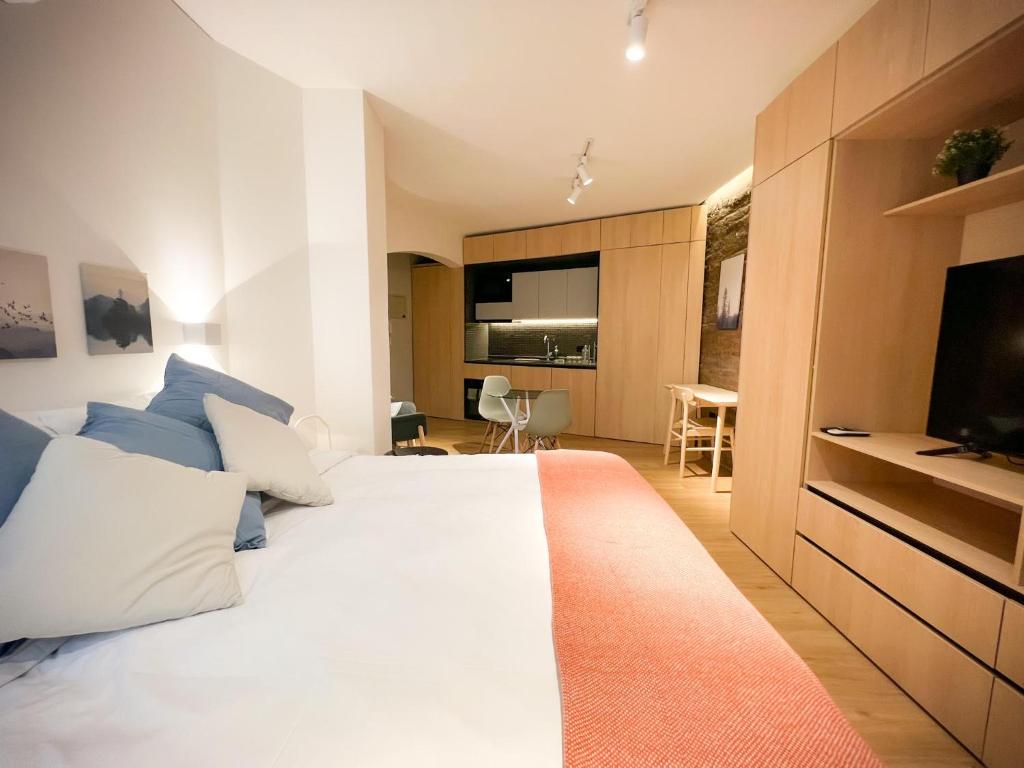 een slaapkamer met een groot wit bed en een televisie bij Encantador Depto tipo Studio en Lastarria Servicio HOM in Santiago