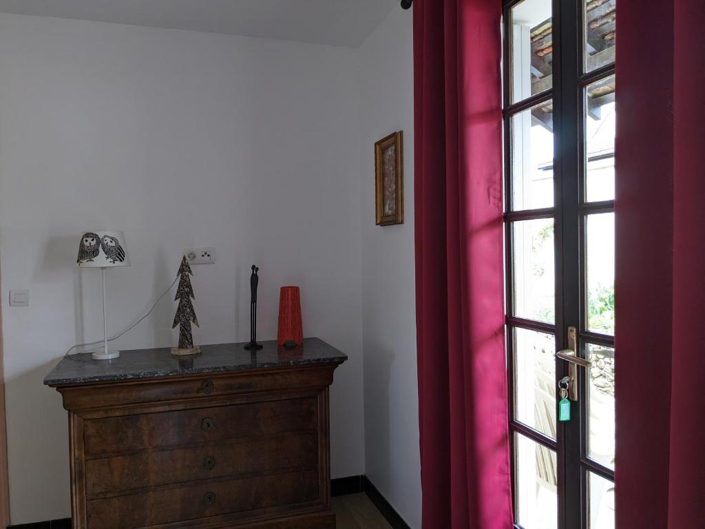 a room with a dresser and a window with red curtains at Au chalet d'Illiers Combray, grand jardin arboré in Illiers