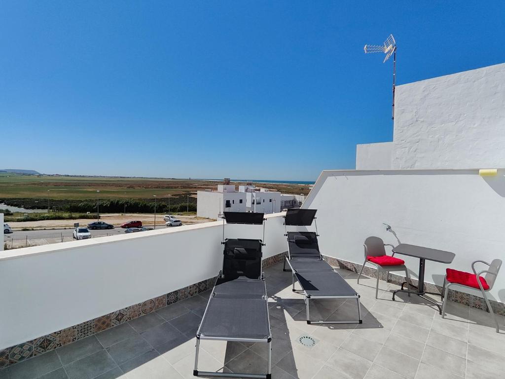 a patio with chairs and a table on a roof at Gemini Conil in Conil de la Frontera