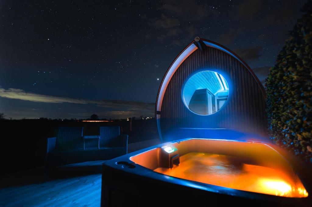 a hot tub on a deck at night at Endrick Escape - Luxury Glamping 