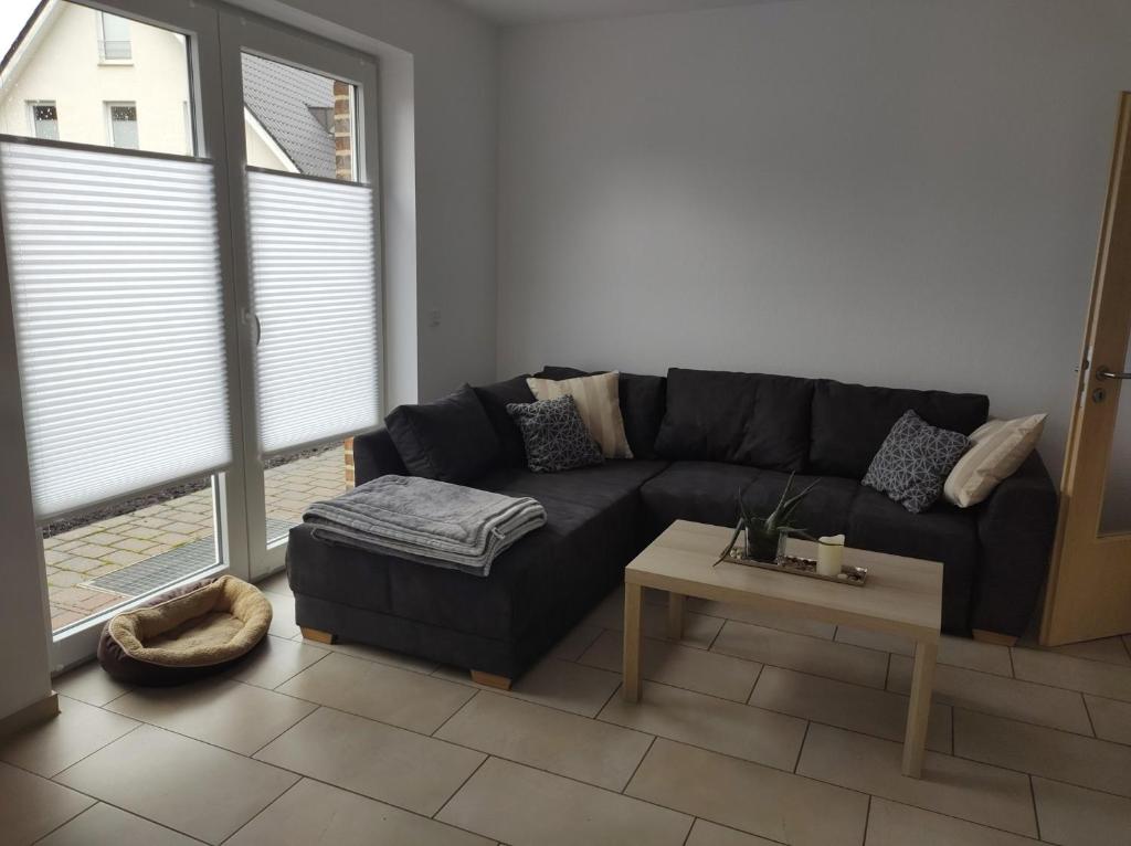 ein Wohnzimmer mit einem schwarzen Sofa und einem Tisch in der Unterkunft FeWo Holunderbusch in Saerbeck