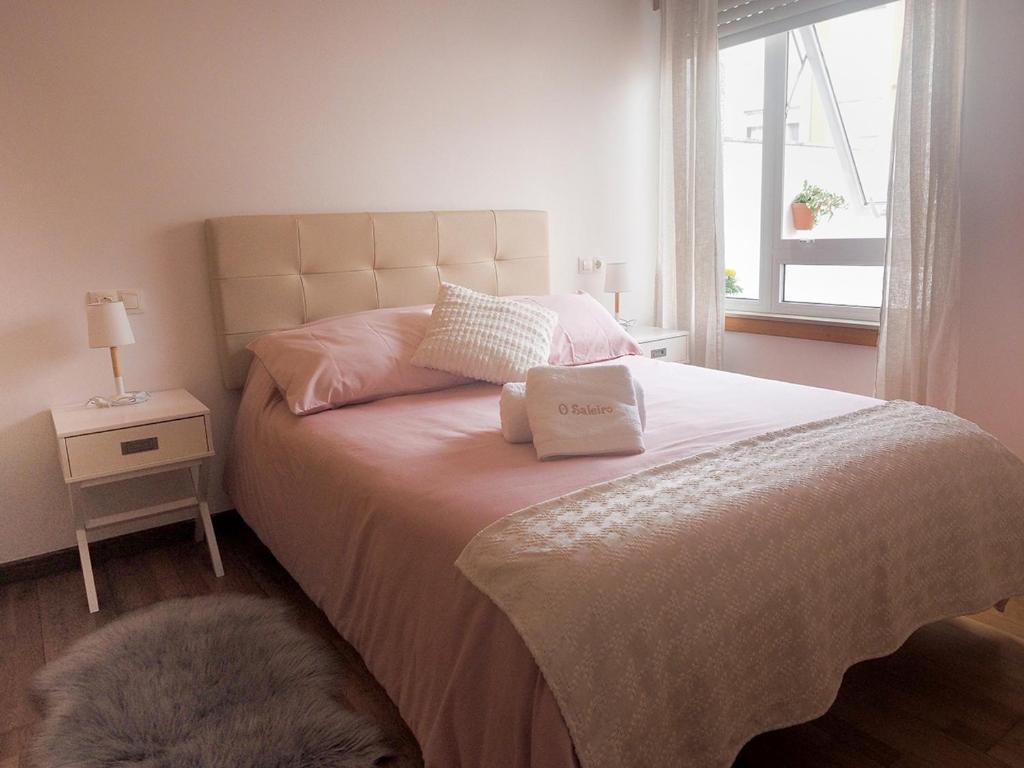 1 dormitorio con 1 cama con 2 almohadas y ventana en Apartamento O SALEIRO, en Padrón