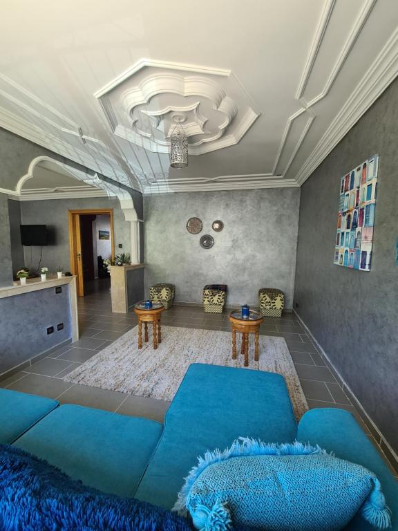 a living room with a blue couch and two tables at Dar Babou in Rabat