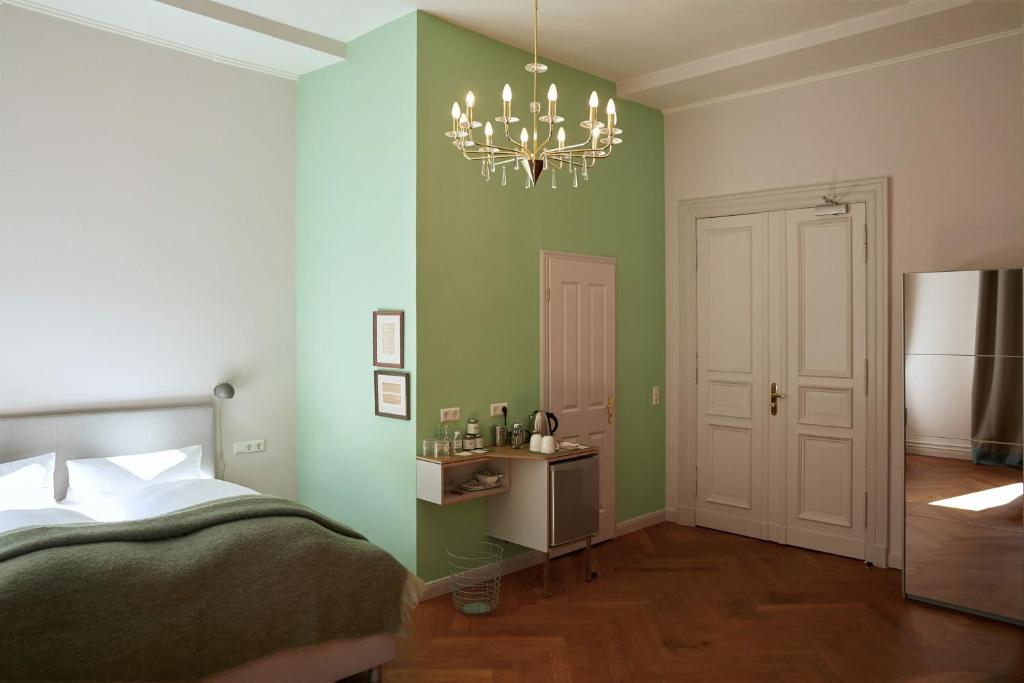 a bedroom with green walls and a bed and a chandelier at Wil7 Boutique Hotel in Berlin