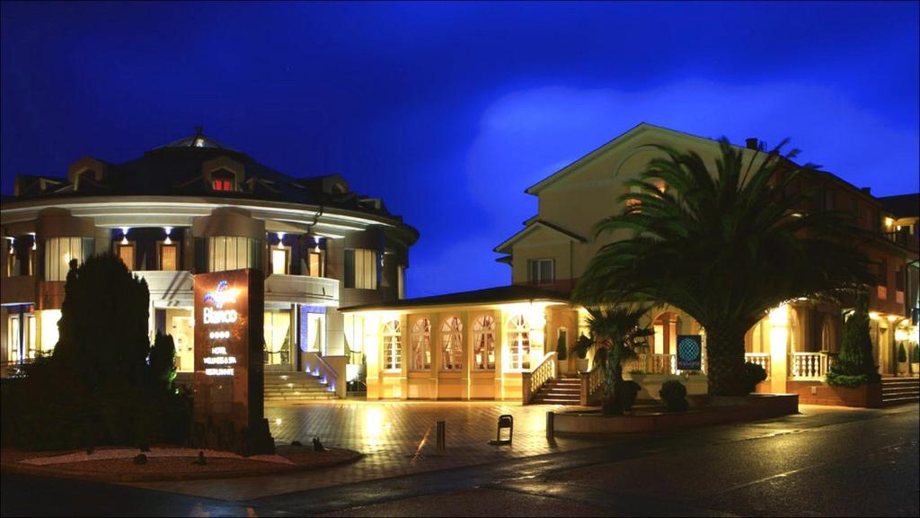 a building with a palm tree in front of it at night at Blanco Hotel Spa in Navia